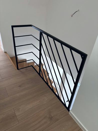 Schwarzes Stahlgeländer mit Diagonalstäben an einem Treppenauge