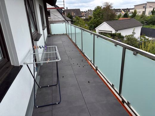 Edelstahl-Glasgeländer mit satiniertem Glas an einem langen Balkon
