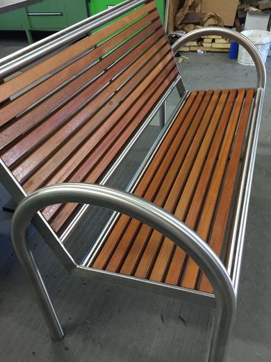 Sitzbank aus Edelstahl und Holz, Seitenansicht mit gebogener Armlehne