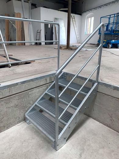Verzinkte Treppe mit Gitterroststufen und Geländer in einer Halle
