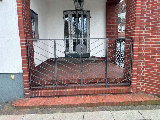 Zweiflügeliges Eingangstor mit Seitenteilen und gespiegeltem Diagonalstab-Muster vor einem Hauseingang